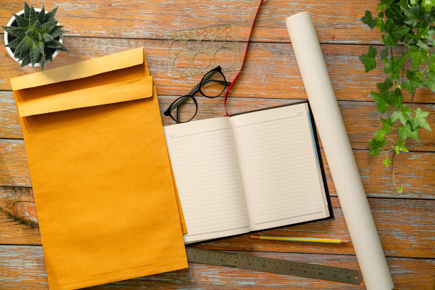 大理石桌上放着一本翻开的笔记本，上面铺着灰色的纸。模型与文本空间。从上面看，桌子上有一副眼镜，仙人掌，木框。全景的照片图片下载