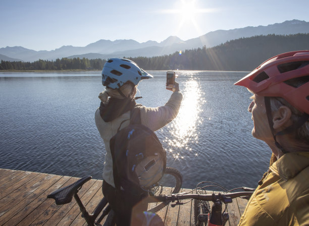 一对骑山地自行车的夫妇在阳光明媚的湖边码头放松图片下载