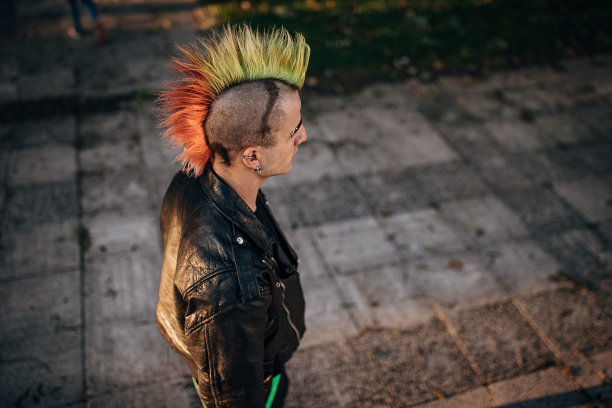 染着莫霍克头的朋克男站在城市的街道上图片下载