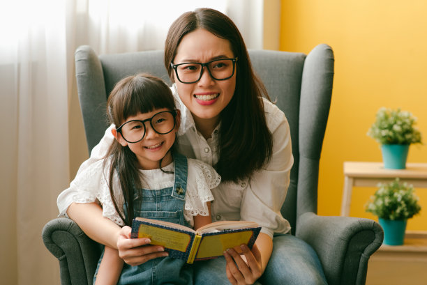 亚洲母亲和女儿在客厅读故事书。图片下载