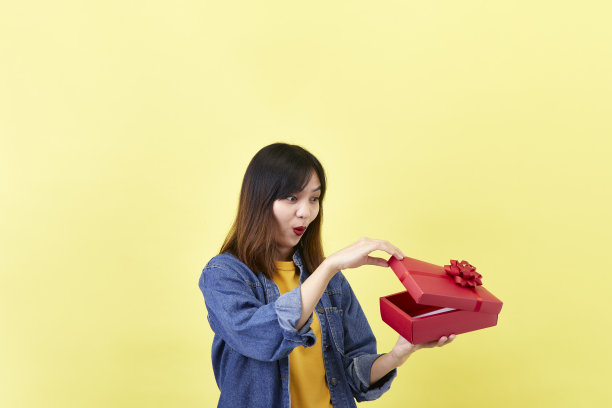 美丽兴奋的年轻亚洲女子手中正在打开一个红色的礼物图片下载