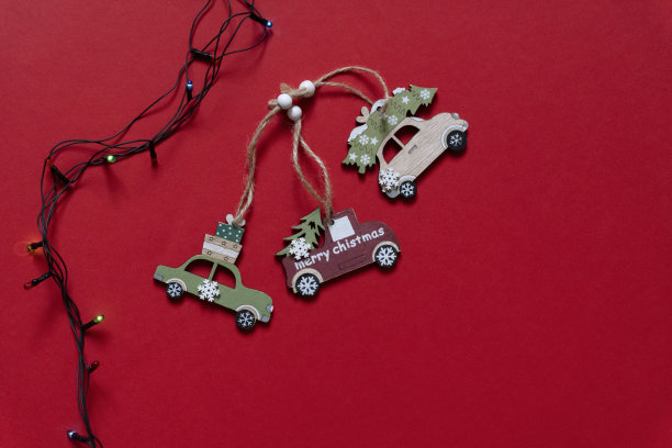 三个木制汽车玩具圣诞树附近彩色的灯泡在红色的背景，俯视图，拷贝空间。图片下载