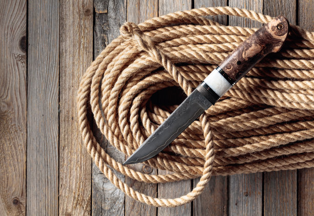 猎人战斗手工刀和麻绳木制背景。图片下载