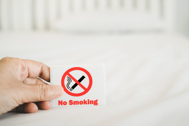 人类的手握着禁止吸烟标志与模糊的卧室，在软焦点图片下载