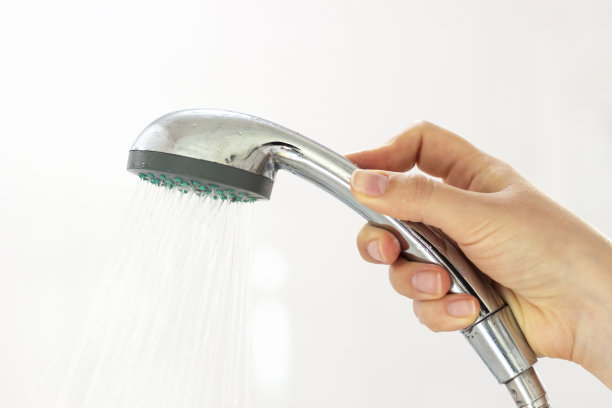 女人的手拿着一个淋浴在白色的背景特写。图片下载