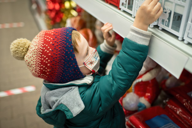 可爱的小男孩戴着防护面具在商店挑选圣诞装饰品图片下载