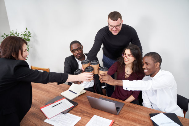 年轻快乐的商务人士在现代化的办公室里一起工作，多民族的团队合作。用咖啡杯敬酒图片下载