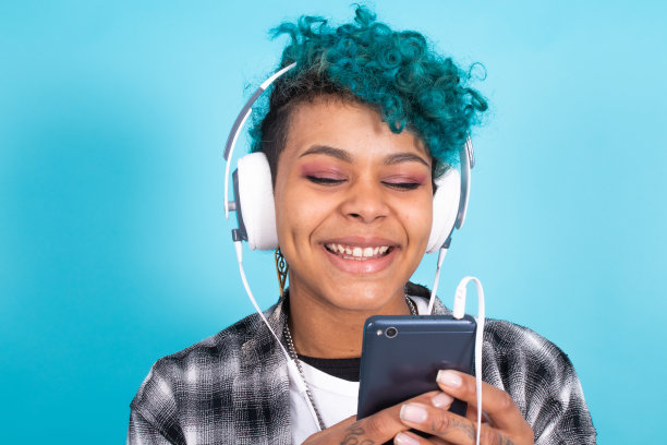 非裔美国女孩或妇女，电话和耳机孤立在蓝色背景图片下载