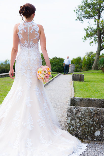 优雅的新娘在婚纱看新郎户外-后视图图片下载