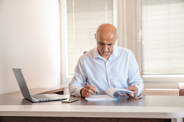 在工作场所用笔记本电脑工作的资深商人图片下载