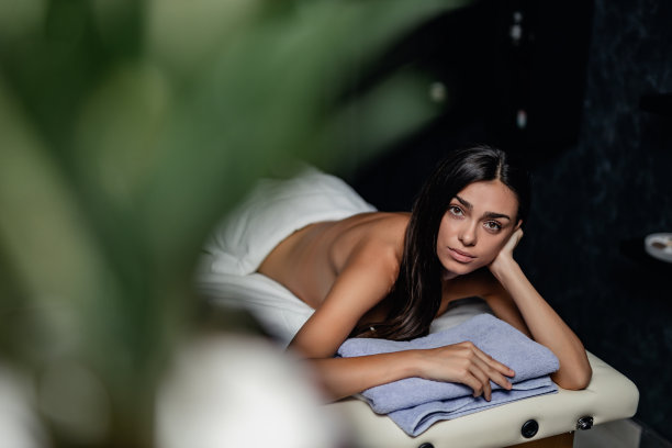 年轻女子披着一条毛巾躺在按摩床上图片下载