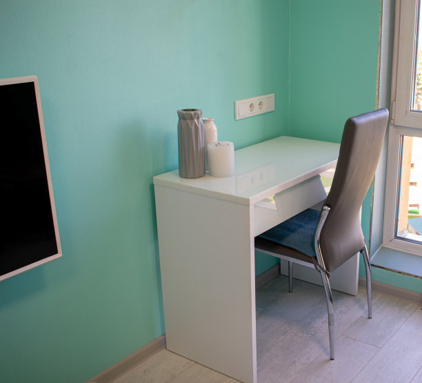 绿色墙壁背景上的花瓶木制化妆桌。房间角落靠窗的桌子和椅子。图片下载