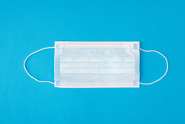 头顶上方平铺布局近距离观看一张医用面膜躺在桌子上的照片，明亮的颜色孤立的背景图片下载