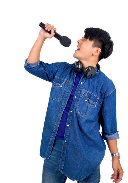 穿着蓝色牛仔裤的亚洲年轻人拿着麦克风唱歌。肖像在白色背景与工作室灯光图片下载