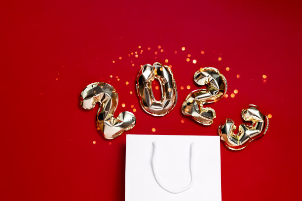 金箔气球2022与一个袋子在喜庆的红色背景与散焦。顶部横向查看拷贝空间。新年和圣诞节的购物理念图片下载