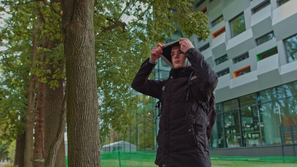 一个时髦的年轻人戴着兜帽看着镜头的肖像。近距离观看千禧男孩在黑色帽衫微笑站在街上。人的情感概念图片下载