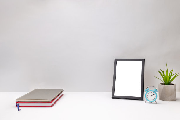 白色书桌上的空白框架模型。灰色的背景墙。办公室或家庭工作场所。工作计划的概念。贺卡模板图片下载