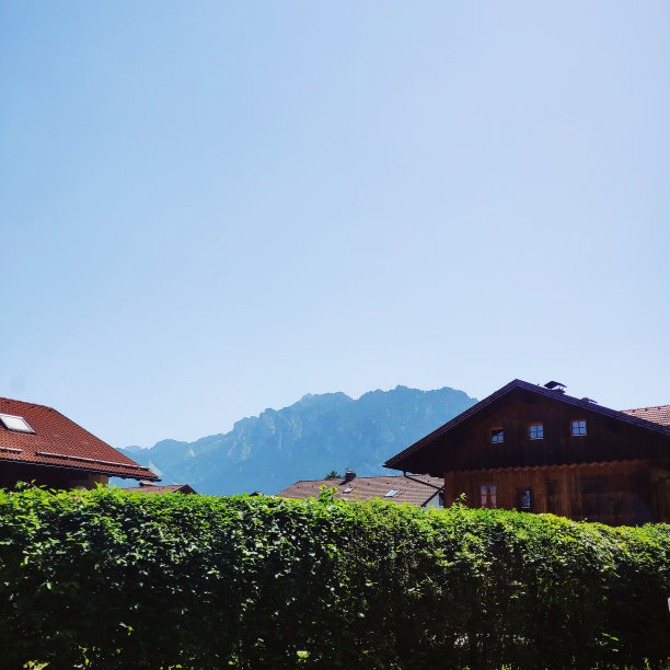 在阳光明媚的日子里，可以欣赏到阿尔卑斯山的田园风光，还有房屋和蓝天图片下载