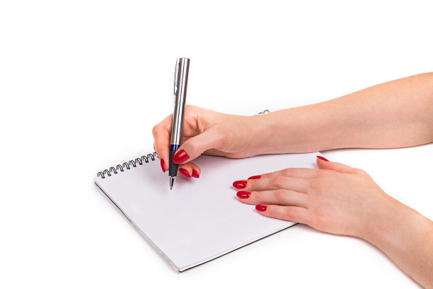指甲的设计。手与明亮的红色圣诞节美甲在白色的背景。女性手的特写。艺术指甲。女人用钢笔在笔记本上写字图片下载