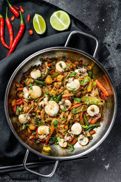 用炒锅炒乌冬面、墨鱼和蔬菜。黑色背景。俯视图图片下载
