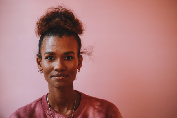 一个微笑的女人的肖像，穿着一件DIY的扎染衬衫，背景是柔和的图片下载