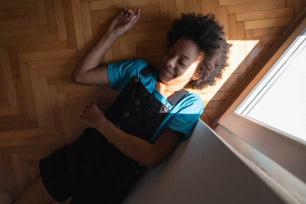 可爱微笑的非洲裔美国女孩躺在镶木地板上图片下载