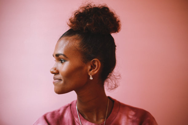 一个微笑的女人的侧面肖像，穿着一件DIY扎染衬衫在一个柔和的背景图片下载