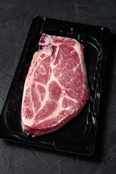 未开封的真空包装猪肉牛排孤立在黑色背景，没有标签。黑色背景。前视图。空间的文本图片下载