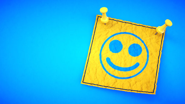 一张黄色的笑脸纸条，用别针别在蓝色的背景上。图片下载