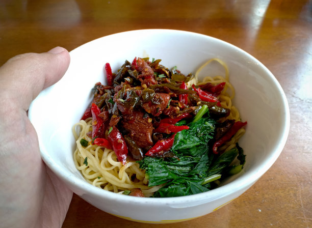 印尼的食物。辣的鸡肉面条。与蔬菜和红辣椒片一起盛在碗里。在一张木桌上。非常美味可口图片下载