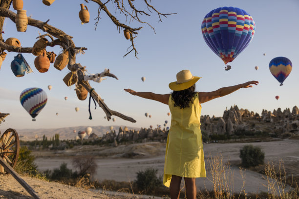 在土耳其卡帕多西亚，美丽的女人看着彩色的热气球飞过山谷。图片下载