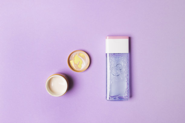 化妆瓶和开瓶与奶油在紫色的纸背景图片下载