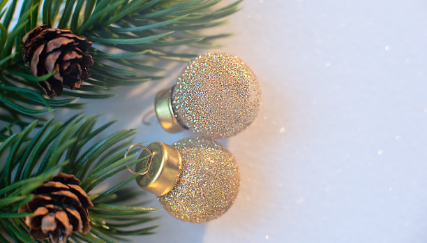 金色的圣诞球在白色的背景与辉光散焦云杉松果。有选择性的重点。宏,极简主义的概念。圣诞节，冬季贺卡，海报。笔记本封面图片。图片下载