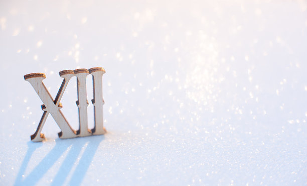 木质十二罗马数字在白色背景与辉光散焦。有选择性的重点。宏,极简主义的概念。圣诞节，冬季贺卡，海报。笔记本封面图片。新年快乐。图片下载