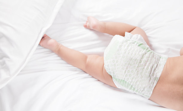 穿着尿布的小男孩躺在床上。图片下载