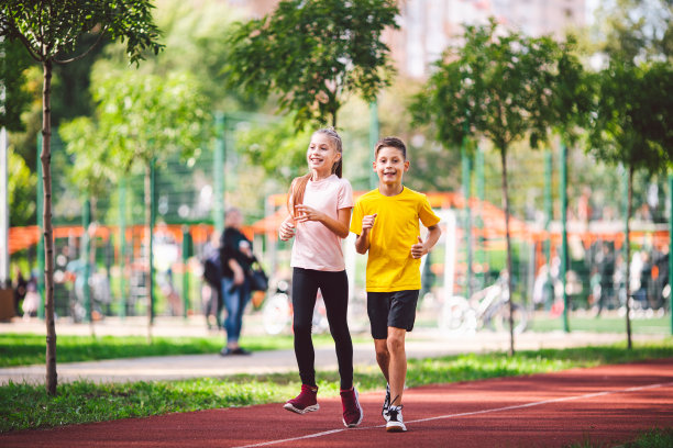青春期前活跃的娱乐和运动儿童。10岁的白种双胞胎男孩和女孩在穿过公园的红色橡胶跑道上慢跑。孩子们的弟弟和妹妹在户外跑步机上跑步图片下载