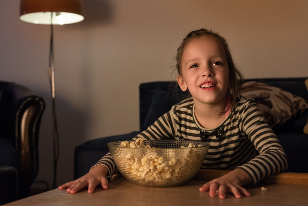 坐在客厅里吃爆米花看电视的孩子图片下载