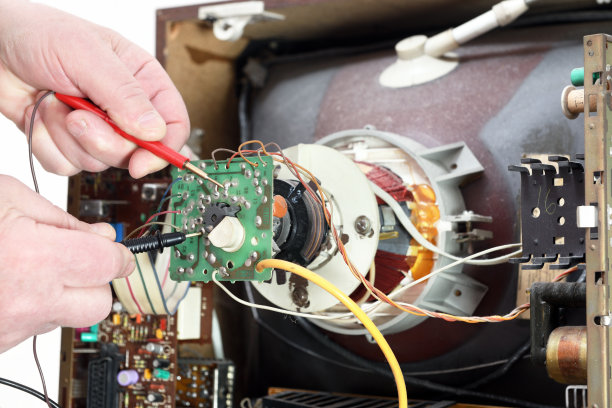 旧显像管电视机的修理。一个电工正在修理一台旧电视，用测试仪检查是否有故障。图片下载