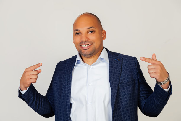 年轻的非洲裔美国人商人的肖像自信地展示和指向手指、牙齿和嘴。健康的概念。站在灰色的背景上。图片下载