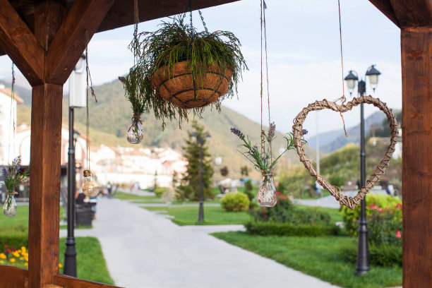 在户外的山景平台上悬挂植物花盆、花卉花瓶和木制装饰品。图片下载