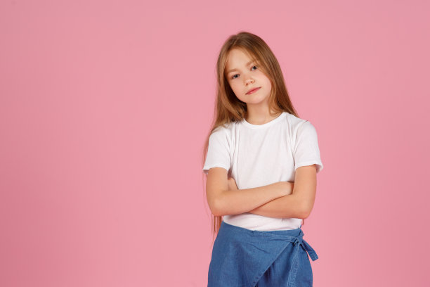一个7岁的小女孩，穿着一件白色的衬衫，在粉红色的背景下，快乐和幸福的情绪。本空间图片下载