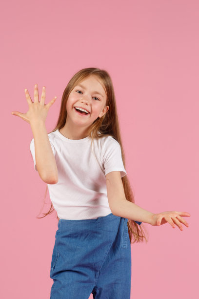 一个7岁的小女孩，穿着一件白色的衬衫，在粉红色的背景下，快乐和幸福的情绪。本空间图片下载