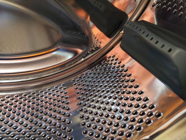 洗衣机的滚筒从里面。闪亮的金属罐，有孔和凸起。不锈钢表面带孔，由不锈钢板材制成。洗衣机的内部视图图片下载