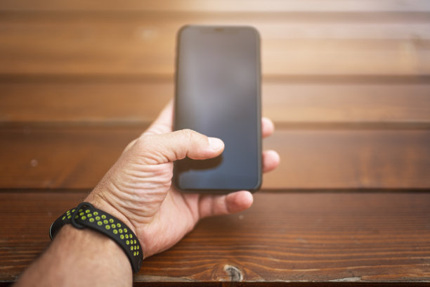男性手与智能手机和木制背景图片下载