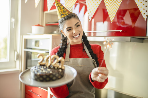 一名年轻女子正在制作巧克力蛋糕，蛋糕上点燃了2021年的数字蜡烛图片下载