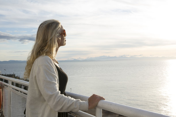女人从栏杆上看着平静的海湾图片下载