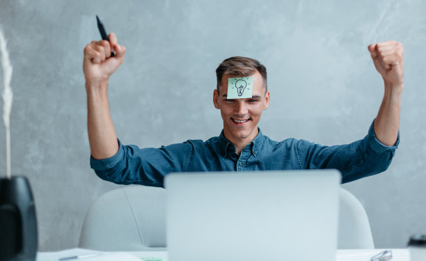 快乐的年轻人看着他的笔记本电脑屏幕图片下载