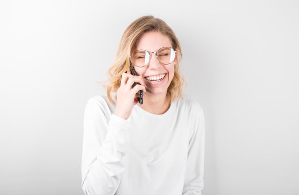 快乐的年轻女孩拿着电话，微笑着接听电话图片下载