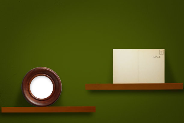 空白的古董明信片和空白的圆形相框放在一个木架子上，背靠深绿色的墙壁图片下载