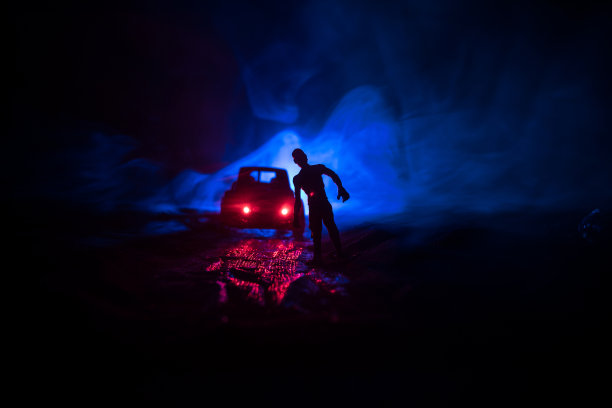 一辆停在路上的车点燃了僵尸的照片。可怕的僵尸剪影夜晚附近的汽车。小型装饰。图片下载
